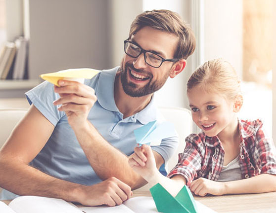 Padre e hija jugando haciendo volar dos aviones de papel