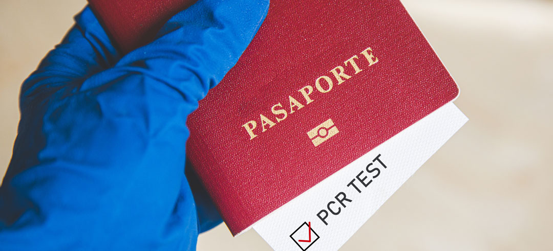 Persona sosteniendo pasaporte con guantes y resultado de test PCR confirmado