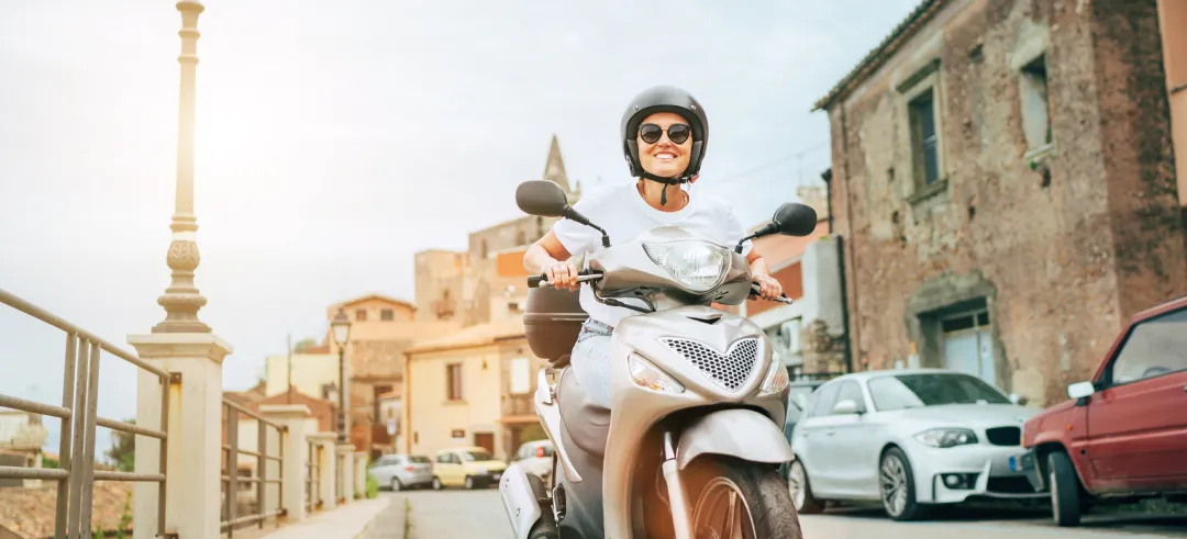 Mujer circulando con una motoneta por una ciudad